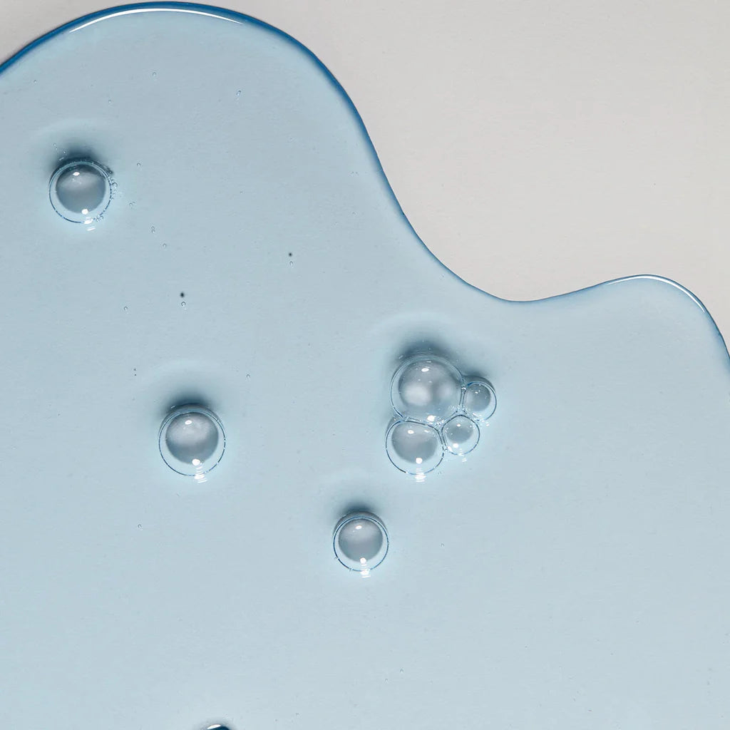 Close-up of a blue glass object with bubbles on a light gray background