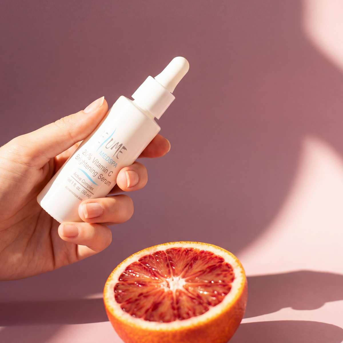 A hand holding a bottle of Elume 20% Vitamin C Brightening Serum.