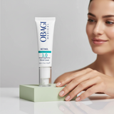 Elume Med Spa Obagi Retinol 1.0 serum tube standing on a green block with a woman smiling in the background