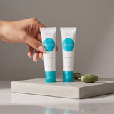 Elume Med Spa Obagi360 Retinol 0.5 tubes held by a hand next to a green jade roller on a concrete display block.